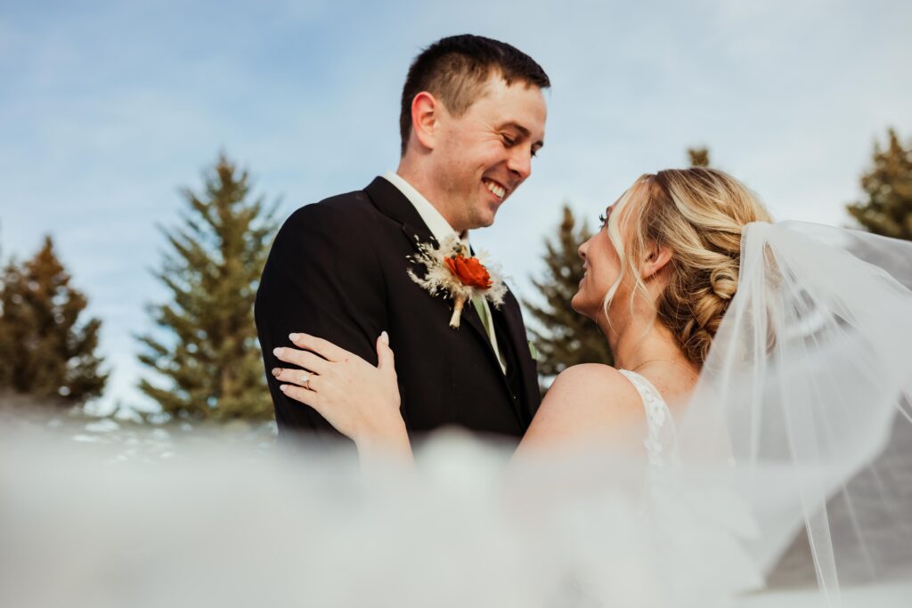 Bride and Groom Smiling under wedding veil 