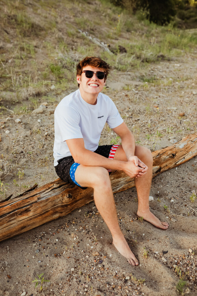 senior boy posing for senior portraits in chubbies and a Patagonia tee on the beach