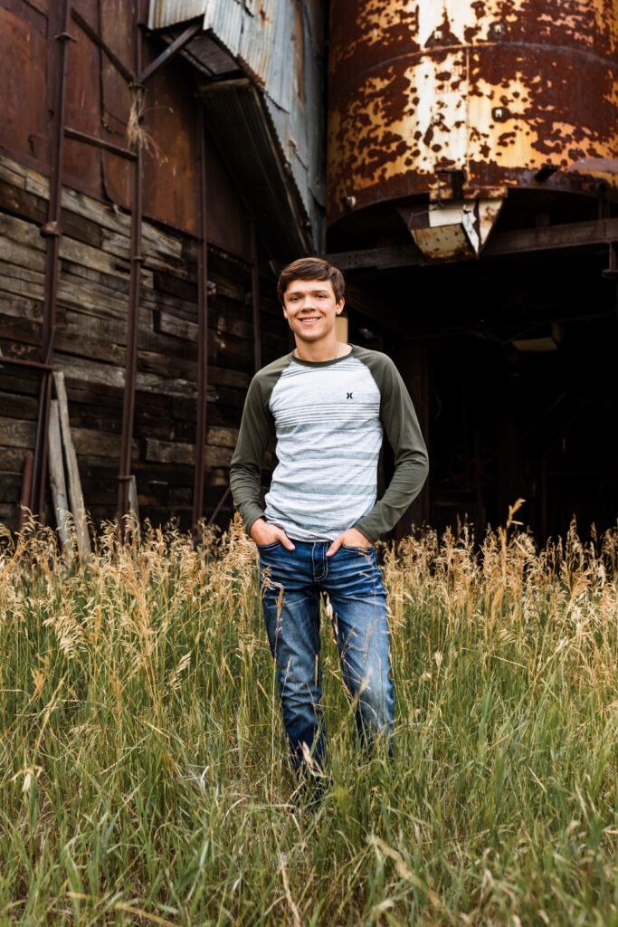 senior boy posing for senior portraits in jeans and striped tee shirt