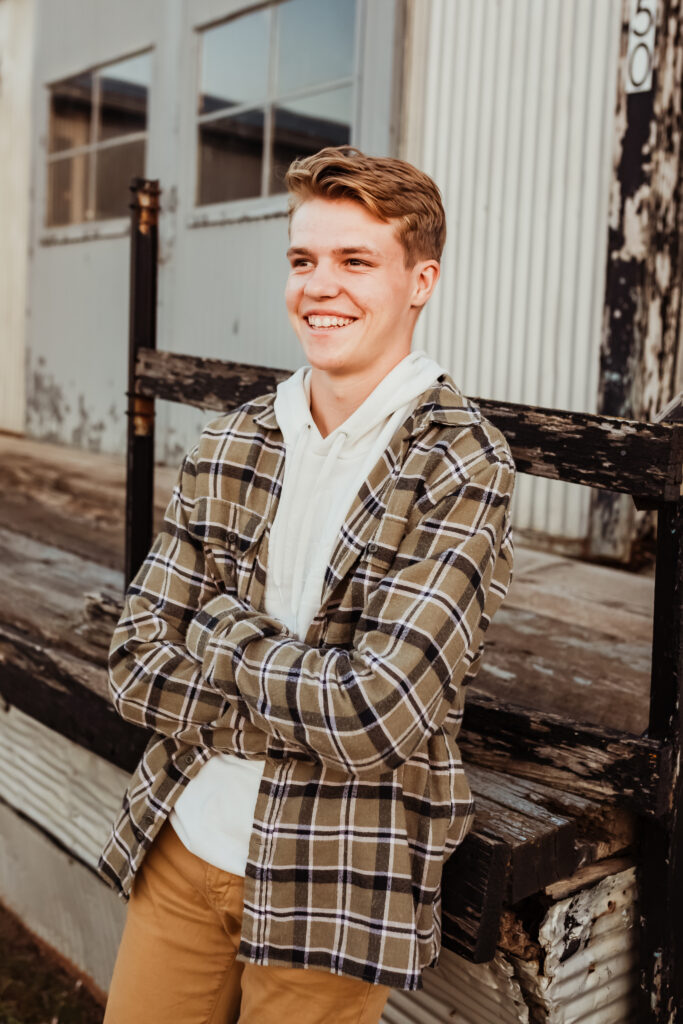 senior boy posing for senior portraits in a flannel with khaki pants